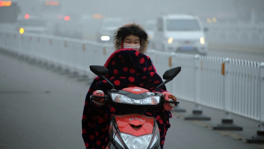 Une femme circule le visage masqué pour se protéger de la pollution le 24 décembre 2015 à Bozou
