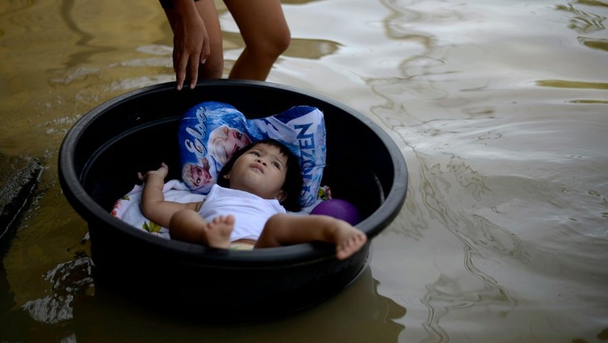 Un enfant allongé dans une bassine en plastique flotte au dessus de l'eau à Calampit Bucalan, à Manille, le 24 décembre 2015