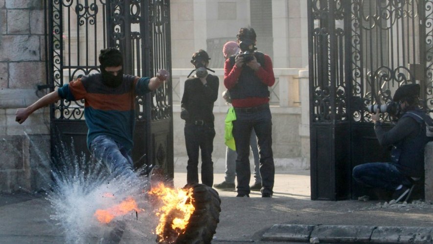 Un manifestant palestinien fait rouler un pneu enflammé lors d'affrontements avec les forces de sécurité israéliennes à l'entrée principale de la ville de Bethléem (Cisjordanie), le 25 décembre 2015.