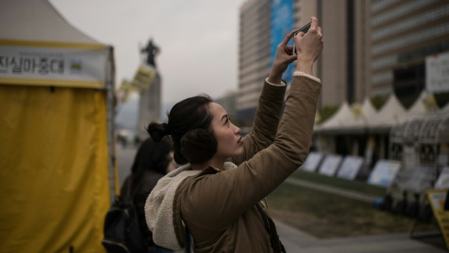 Une femme prend en photo une manifestation anti-gouvernementale, dans le centre de Séoul, le 3 novembre 2016