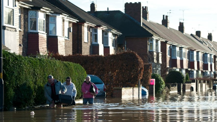 Des gens marchent dans une rue inondée à York (nord de l'Angleterre), le 27 décembre 2015