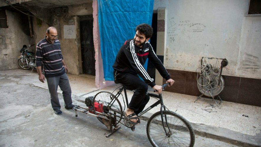 Un Syrien pédale sur un vélo relié à une vieille batterie pour produire de l'électricité, le 31 octobre 2016 à Alep