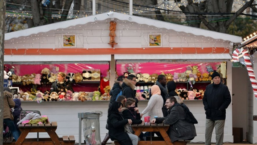 Des personnes s'asseoient devant un stand de jouets, au marché de Noël à Paris, le 24 décembre 2015