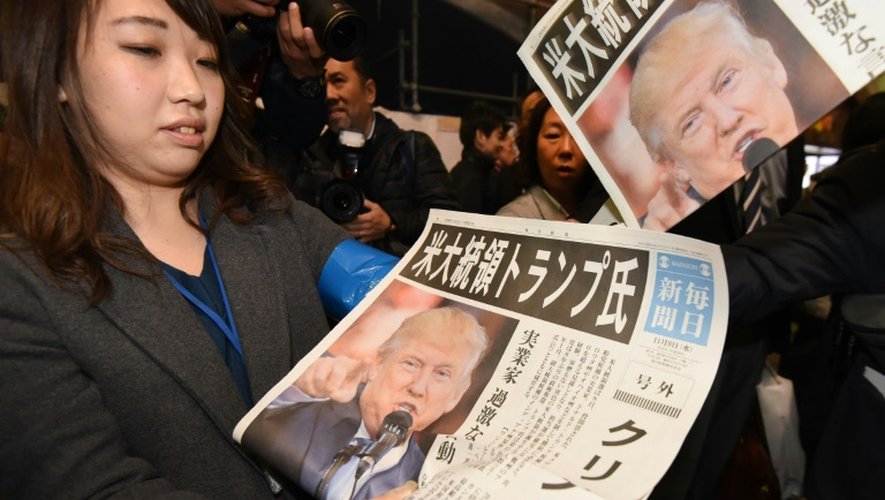 Une Japonaise montre la Une du quotidien Yomiuri, avec l'annonce de la victoire de Trump, le 9 novembre  2016 à Tokyo