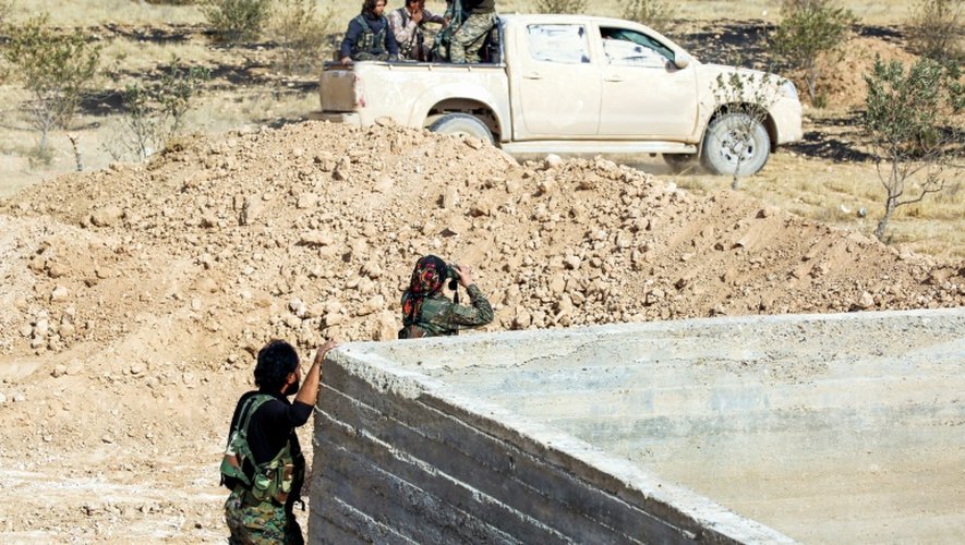 Une membre des Unités de protection de la femme kurde (YPJ) regarde le champ de bataille avec des jumelles à côté du village de Mazraat Khaled, à environ 40 kms du groupe d'État islamique Capitale de Raqa, le 9 novembre 2016