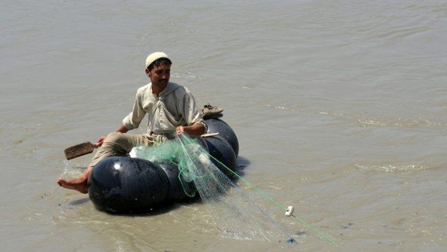 Un pêcheur pakistanais cherche des poissons à pêcher, assis sur une chambre à air, le 18 août 2016 sur la rivière Kaboul, près du village Hajji Zai (nord-ouest du Pakistan)