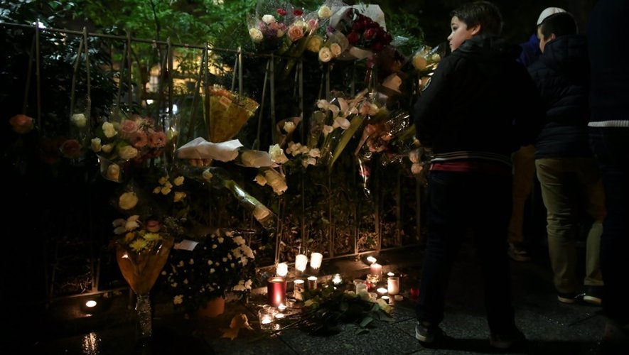Des gens se réunissent autour des fleurs et des bougies déposées près du Bataclan, le 12 novembre 2016 à Paris