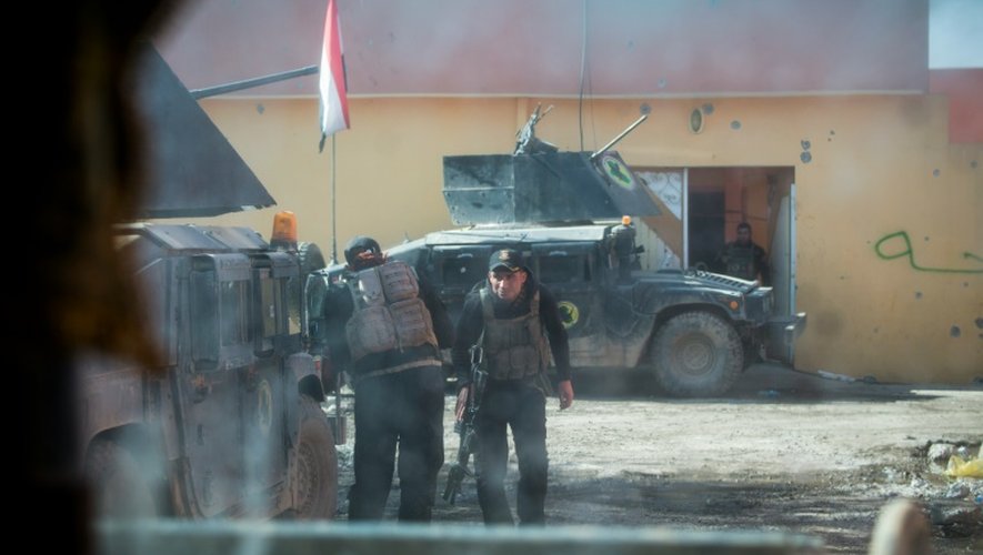 Une photo prise par la fenêtre blindé montre des soldats de la 2ème division des forces spéciales irakiennes se couvrant derrière leurs véhicules sous le feu d'un tireur de l'EI, le 12 novembre 2016, dans le quartier Al-Samah, à l'est de Mossoul