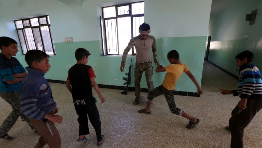 Des garçons jouent au foot dans leur école avec un soldat des forces irakiennes, le 12 novembre 2016, dans le village de Jarif, à environ 45 kilomètres au sud de Mossoul