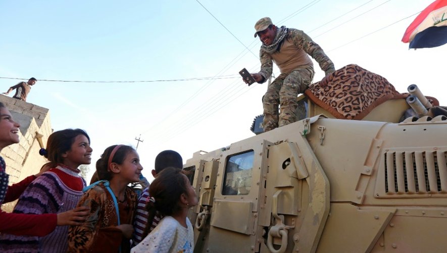 Des enfants rient avec un soldat des forces irakiennes patrouillant dans une rue du village de Jarif, à environ 45 kilomètres au sud de Mossoul, le 12 novembre 2016