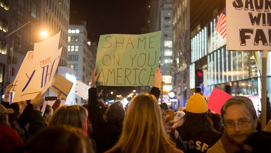 Une personne brandit une pancarte "honte à toi Amérique" lors d'une manifestation contre l'élection de Donald Trump le 13 novembre 2016 à New York