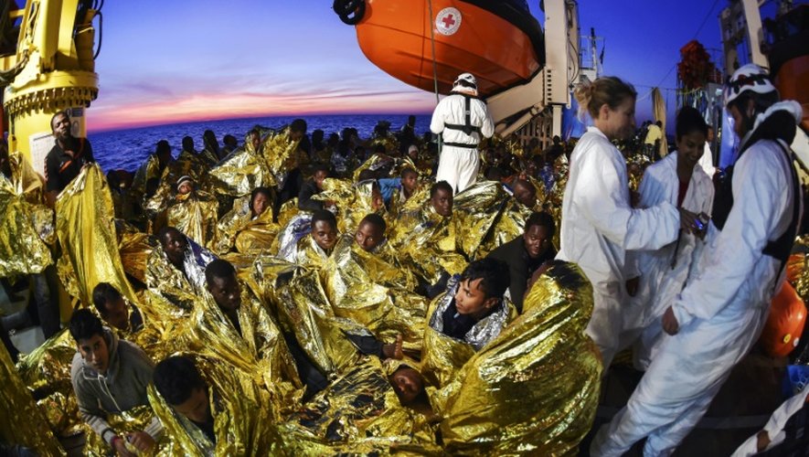 Des sauveteurs d'une ONG et de la Croix-Rouge italienne s'occupent de migrants enveloppés dans des couvertures de survie, après une opération de sauvetage au large des côtes libyennes, le 5 novembre 2016