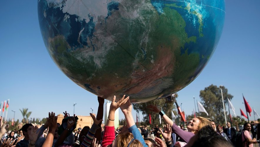 Des membres des délégations internationales à la COP22 jouent avec un globe terrestre géant, le 18 novembre 2016 à Marrakech, au Maroc