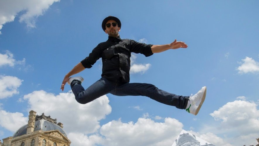 L'artiste et photographe français JR saute devant la Pyramide du Louvre à Paris le 25 mai 2016