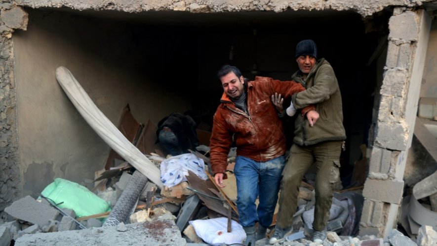 Deux syriens sortent des décombres d'un immeuble après des bombardements dans le quartier d'al-Hamra à Alep, tenu par les rebelles, le 20 novembre 2016