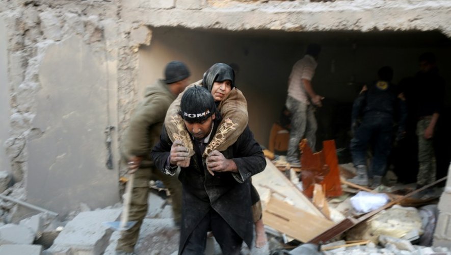 Un secouriste syrien porte une femme sauvée des décombres d'un immeuble après des bombardements dans le quartier d'al-Hamra à Alep, tenu par les rebelles, le 20 novembre 2016