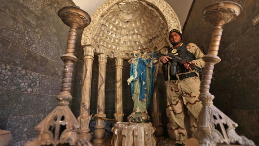 Un soldat des "Brigades de Babylone" près d'une statue de la vierge Marie décapitée par les jihadistes de l'EI, le 22 novembre 2016 à Khidr Ilyas, en Irak