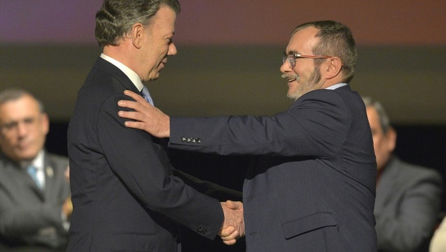 Le président colombien Juan Manuel Santos (G) et le chef de la guérilla des FARC Timoleon Jimenez, alias Timochenko, se serrent la main lors de la deuxième signature de l'accord de paix historique, le 24 novembre 2016 à Bogota
