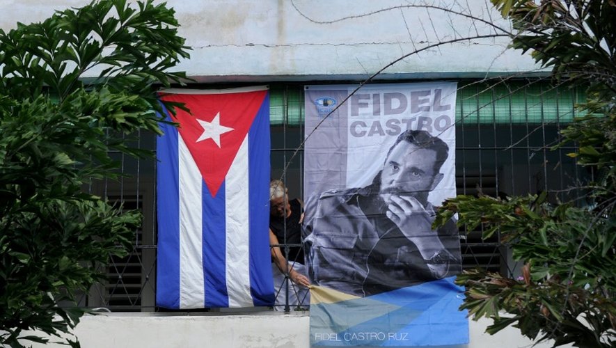 Une Cubaine accroche une photo de Fidel Castro à la fenêtre de sa maison, le 28 novembre 2016 à La Havane