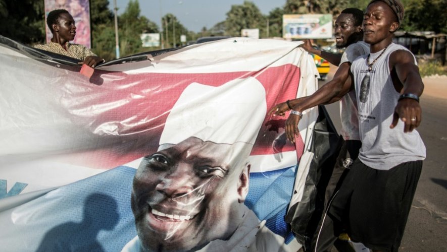 Des partisans du nouveau président de Gambie, Adama Barrow, déchirent des affiches du président sortant, Yahya Jammeh, à Serekunda le 2 décembre 2016