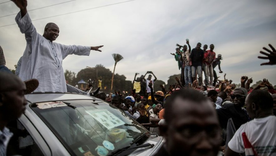 Adama Barrow, porte-drapeau de la coalition des sept partis politiques d'opposition en Gambie, salue les partisans du toit de sa voiture lors d'un rassemblement dans la zone tampon de Talinding le 29 novembre 2016