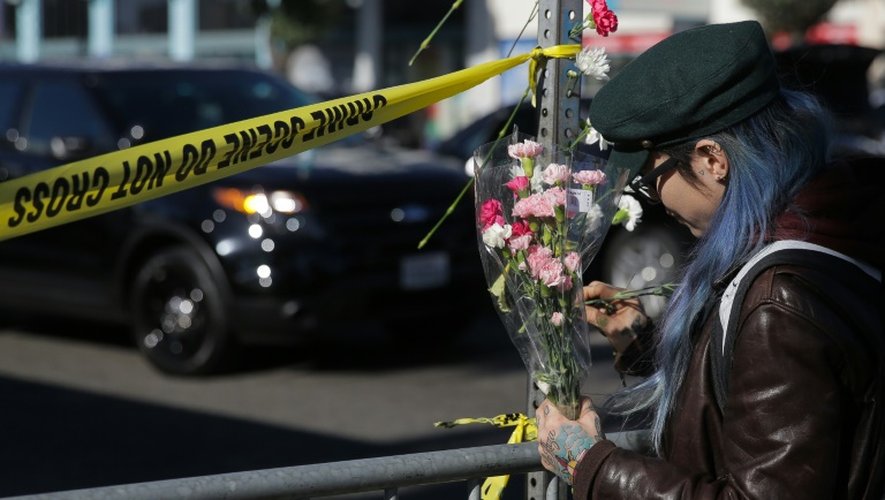 Une femme place des fleurs près du lieu d'un incendie à Oakland, Californie le 3 décembre 2016