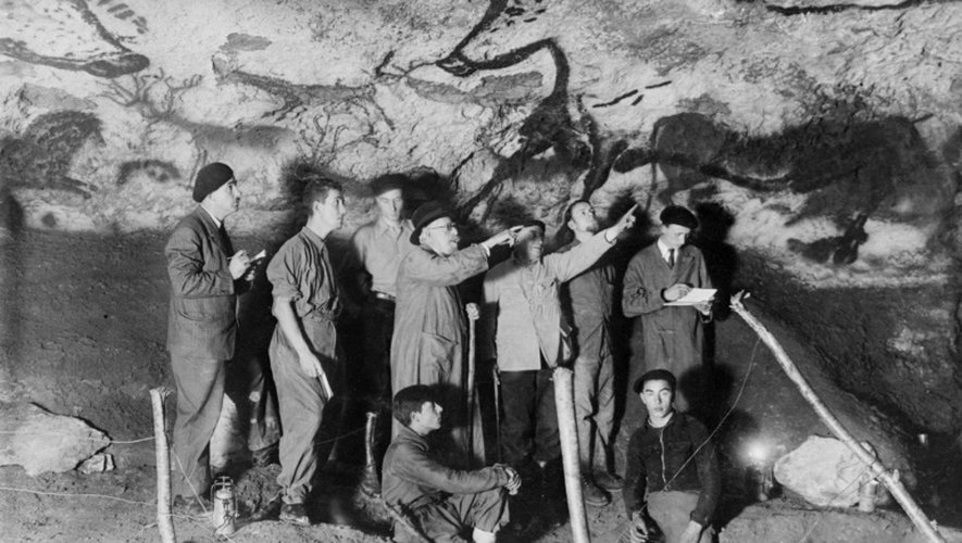 Le paléontologue et préhistorien Henri Breuil (3ème D) observe le panneau des aurochs dans la salle des taureaux de la grotte de Lascaux en 1948 à Montignac en Dordogne, en compagnie d'autres archéologues et de M. Ravidat (D, assis) et J. Marsal (G, assis).