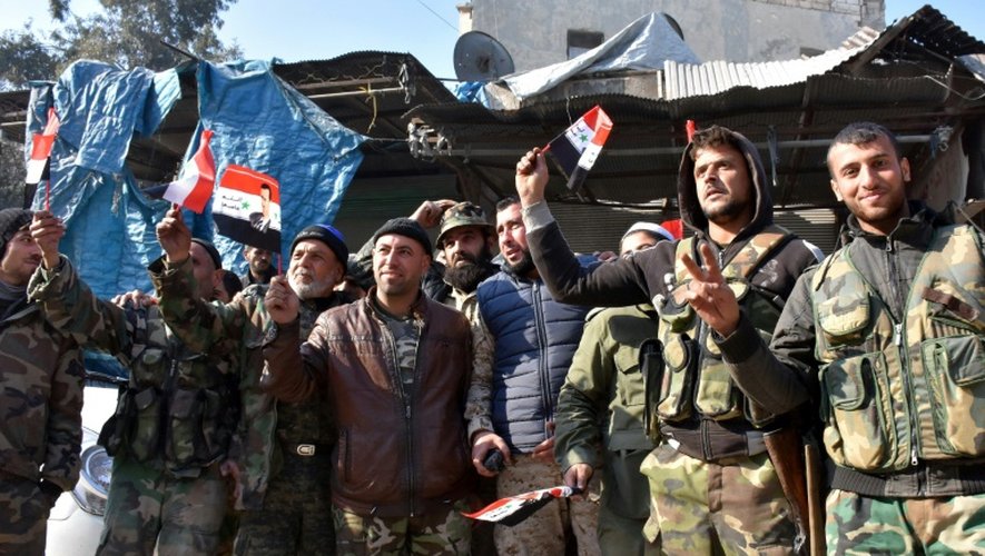 Des soldats du régime agitent des drapeaux syriens avec le portrait d'Assad dans le quartier de Bab al-Nairab à Alep le 10 décembre 2016