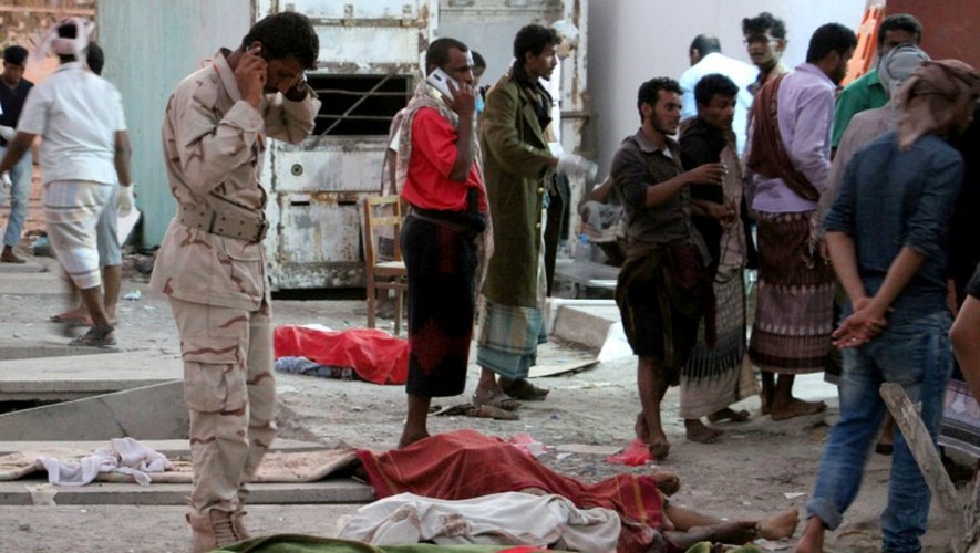 Des Yéménites autour de corps couchés sur le sol, tués dans un attentat suicide dans une caserne d'Aden, le 10 décembre 2016