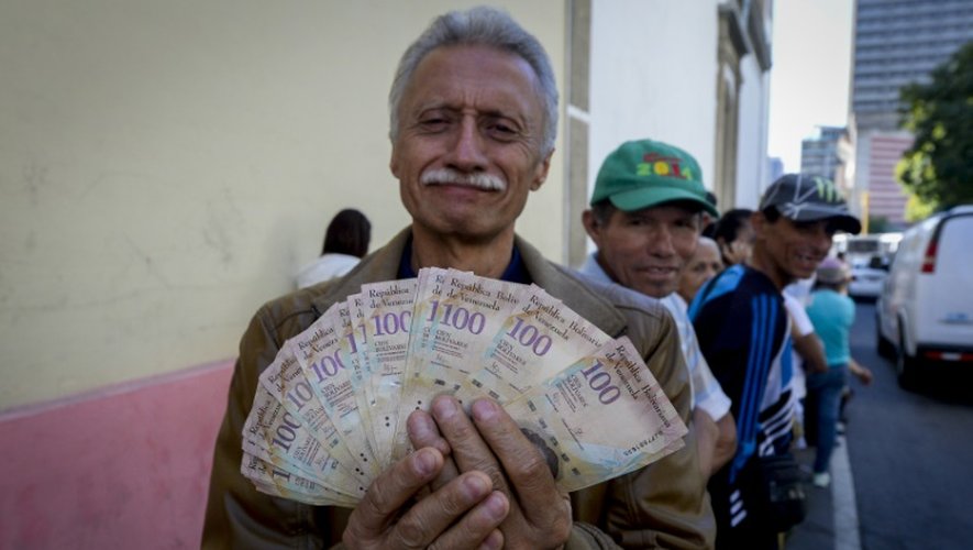 Un homme montre ses billets de 100 bolivars en attendant de pouvoir les échanger à la banque centrale du Venezuela à Caracas, le 16 décembre 2016