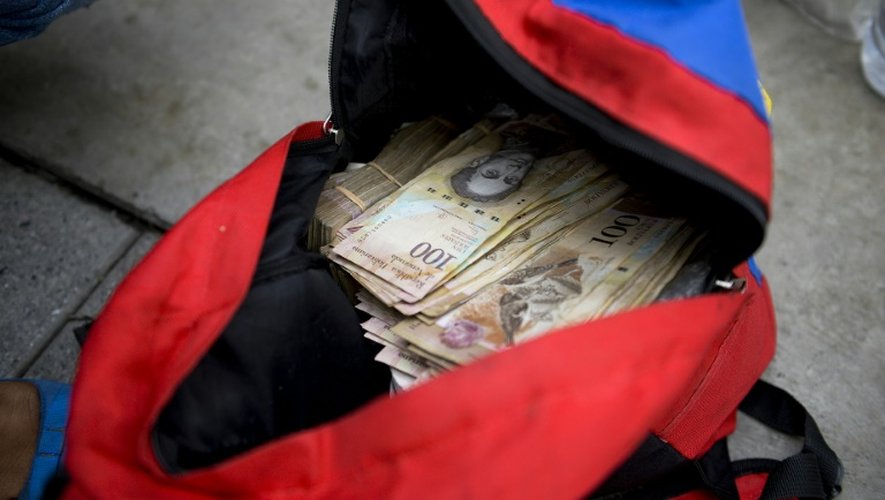 Une femme montre un sac rempli de billets de 100 bolivars qu'elle veut changer à la banque centrale à Caracas, le 16 décembre 2016