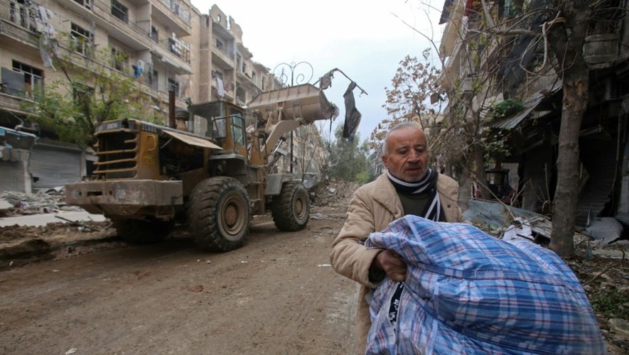 Un Syrien parmi les décombres lors de la réouverture d'une route par les forces pro-gouvernementales à Alep, le 17 décembre 2016