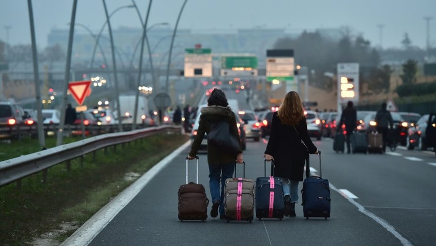 Des voyageurs marchent sur l'autoroute coupée par les chauffeurs de VTC en direction de l'aéroport d'Orly, le 17 déembre 2016