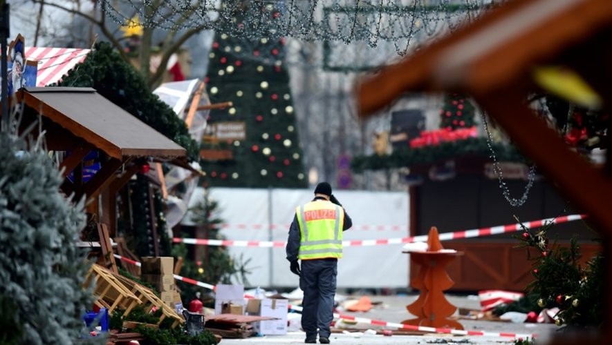 Un policier marche le 20 décembre 2016 dans le marché de Noël près de l'église du Souvenir à Berlin, frappé par un attentat terroriste la veille