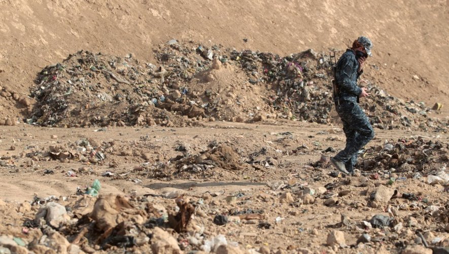 Un membre des forces de sécurité irakiennes au milieu d'une fosse découverte le 7 novembre 2016 à Mosssoul après la reprise de la ville au groupe EI
