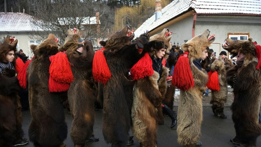 Des roumains vêtus de peaux d'ours dansent dans les rues de Comanesti, le 30 décembre 2016 lors d'un défilé pour chasser les mauvais esprits de l'année écoulée