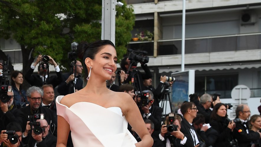 La top-modèle Jessica Kahawaty a foulé le tapis rouge dans une robe sophistiquée, entièrement blanche, jouant sur les volumes et le mouvement, signée de la maison de couture Azzi & Osta. Cannes, le 14 mai 2018.