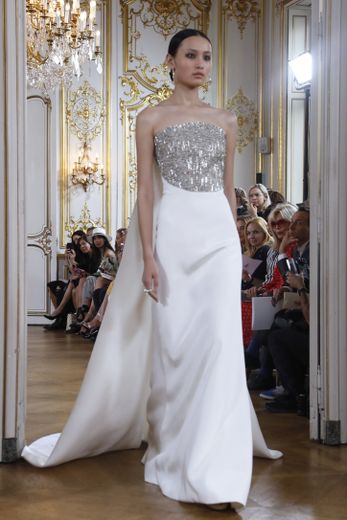 La féminité et la grâce étaient au rendez-vous chez Antonio Grimaldi, qui propose toute une série de robes blanches, ornées de détails scintillants, et de longues traînes. Paris, le 2 juillet 2018.