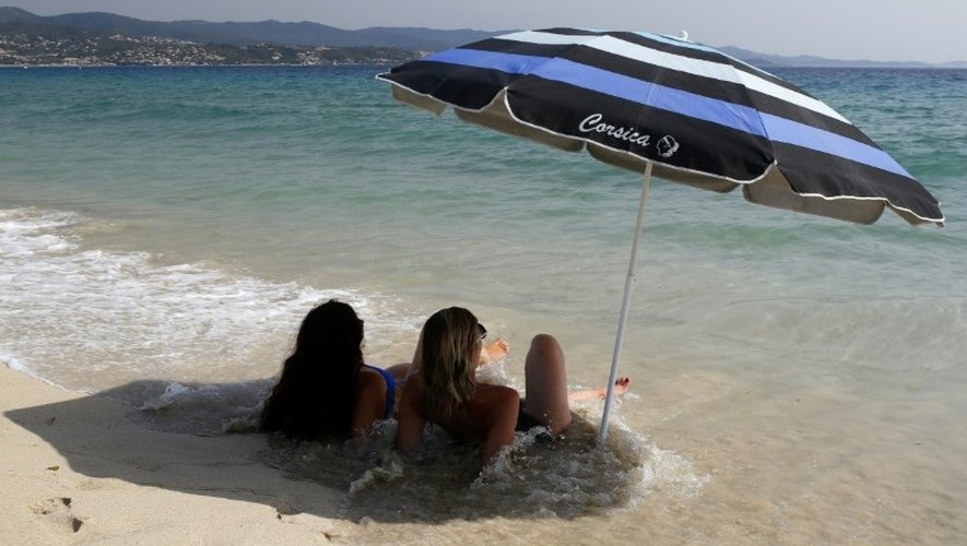 Deux femmes, allongées sur le sable, à l’ombre d’un parasol, sur la plage d’Ajaccio, en Corse. 