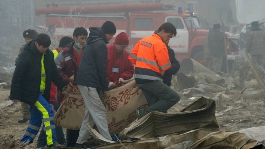 Des sauveteurs évacuent le corps d'une victime du crash d'un avion-cargo turc sur des habitations, le 16 janvier 2017 près de l'aéroport de Bichkek, au Kirghizstan