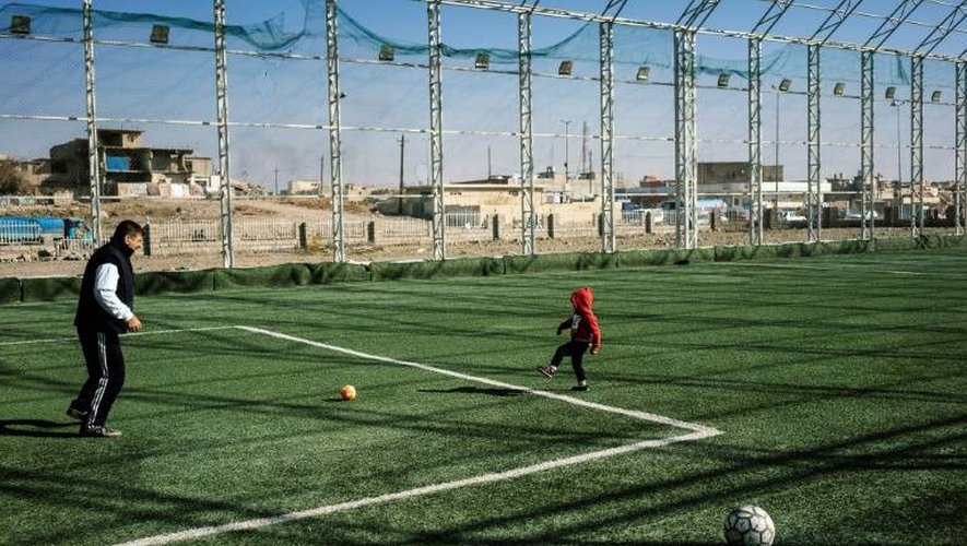 Un Irakien joue au foot avec un enfant à Mossoul, le 11 janvier 2017
