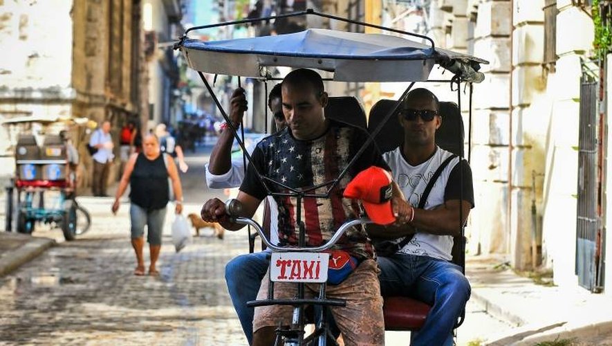 Un Cubain, chauffeur de taxi à trois roues, porte un t-shirt aux couleurs du drapeau américain, le 9 novembre 2016 dans une rue de La Havane
