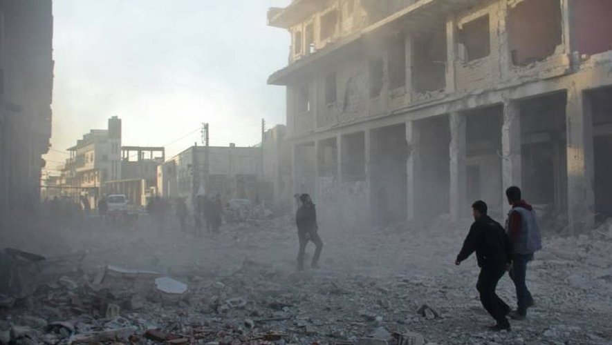 Des Syriens courent dans les débris de la ville de Binnish près d'Idleb après un raid aérien, le 12 janvier 2017