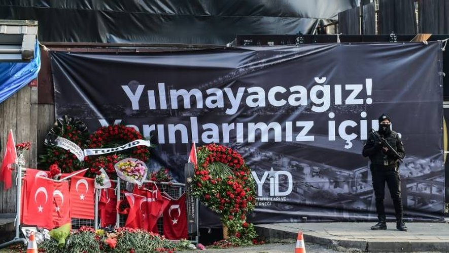 Un policier turc anti-émeute devant une banderole "pour notre avenir nous n'allons pas plier" déployée le 3 janvier 2017 à Istanbul devant la discothèque Reina