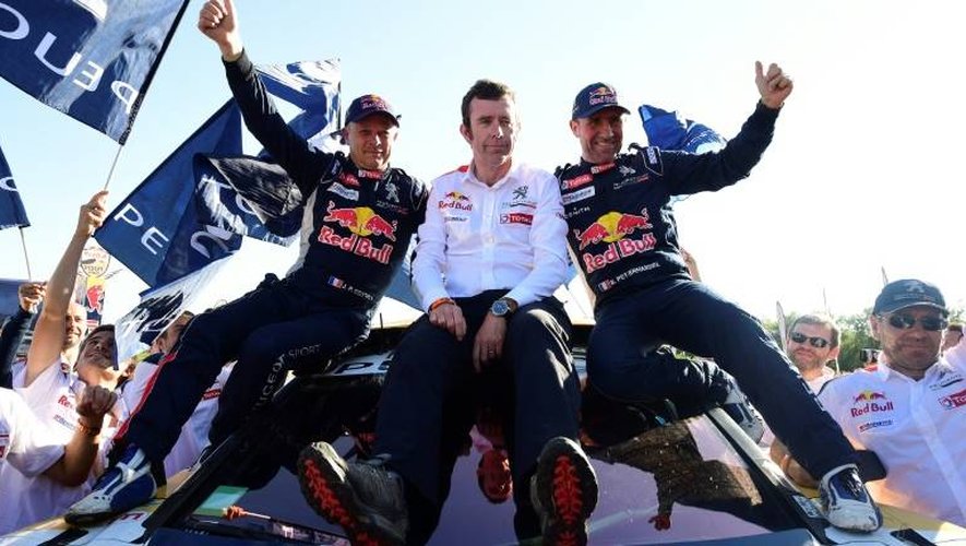 Stéphane Peterhansel (d), son copilote Jean-Paul Cottret (g) et le team manager Peugeot Bruno Famin fêtent leur succès dans le Dakar, le 14 janvier 2017 à Rio Cuarto en Argentine