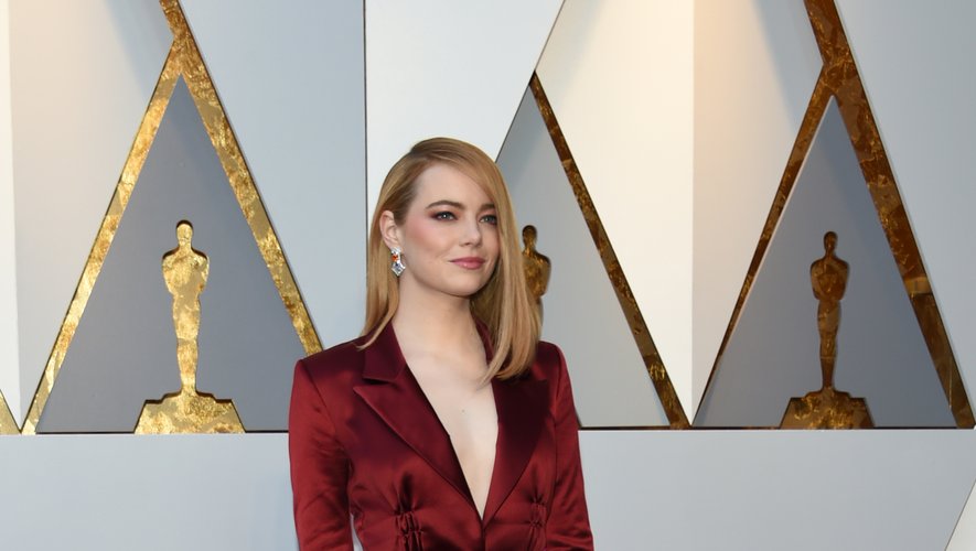 Alors que les robes de soirée sont légion aux Oscars, Emma Stone se démarque et opte pour un pantalon très simple, un blazer rouge satiné, et une ceinture rose. Le tout conçu par Louis Vuitton. Hollywood, le 4 mars 2018.