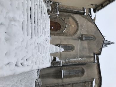 Un superbe bonhomme de neige lève les bras au ciel pour dissuader les aventuriers d’emprunter l’escalier de l’église.