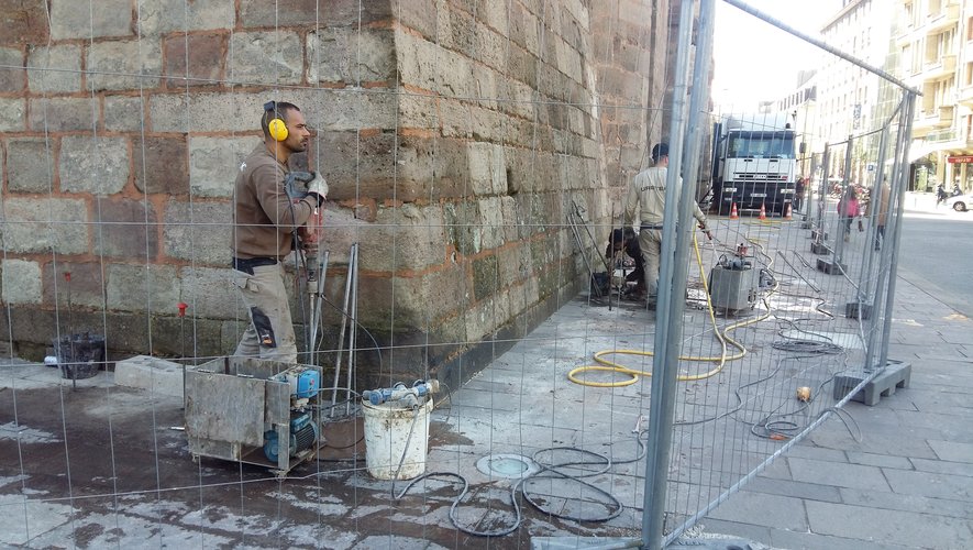 Les techniciens de l'entreprise Uretek en plein percement des orifices au pied de la façade ouest de la cathédrale.