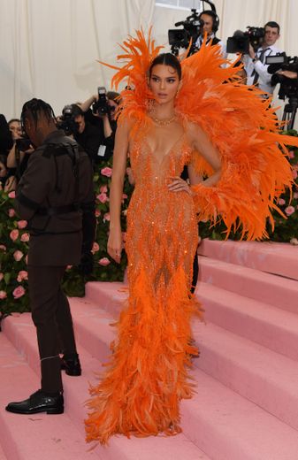 Kendall Jenner mise aussi sur la maison Versace mais choisit une robe d'un orange vibrant, faite de transparence et de plumes. New York, le 6 mai 2019.