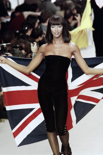 Le mannequin britannique porte avec fierté son drapeau lors du défilé de prêt-à-porter automne-hiver 1994 signé Karl Lagerfeld pour Chanel. Paris, le 10 mars 1994.